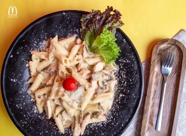 غذای فست فود مادر: پاستا پنه خوشمزه با سس خامه ای، قارچ، مرغ، پنیر و تزیین سبزیجات تازه در بشقاب مشکی.