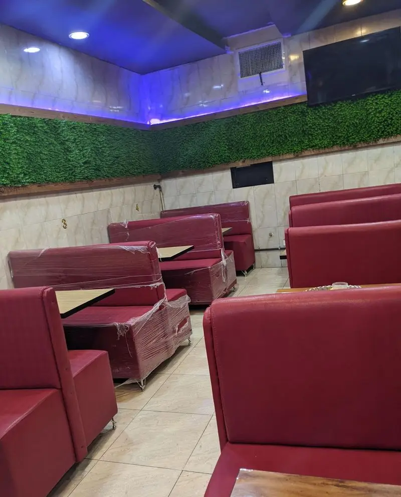 فضای داخلی رستوران جگرسرای خندان، شامل بوفه‌های قرمز تمیز و بسته‌بندی شده، با دیوار سبز مصنوعی و نورپردازی مدرن آبی، محیطی دلنشین.