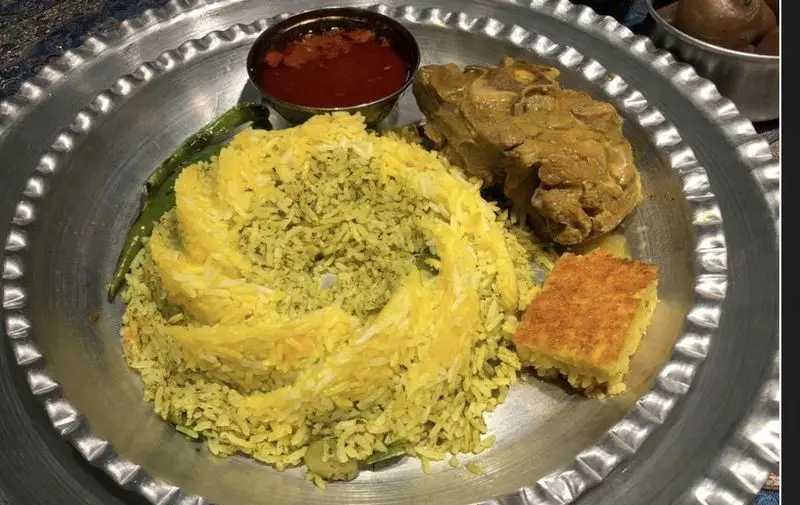 تصویر غذای سنتی ایرانی شامل سبزی پلو با گوشت، ته دیگ زعفرانی، سس و فلفل سبز از رستوران مهدی.