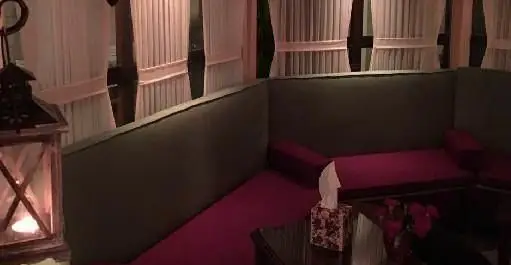 فضای داخلی دنج و دلنشین فست فود بیزی کافه با مبلمان راحت قرمز و سبز، نورپردازی گرم و فانوس شمعی، محیطی آرام برای مشتریان.