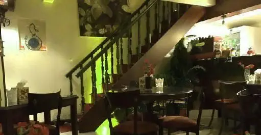 فضای داخلی بیزی کافه، محیطی دنج و جذاب با پله های چوبی شیک، میز و صندلی های راحت و دکوراسیون هنری، مناسب فست فود و کافه.