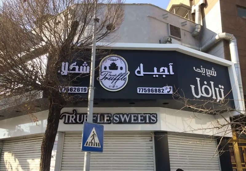 نمای خارجی مغازه شیرینی فروشی ترافل (Truffle Sweets) با تابلو بزرگ، لوگوی Sweet Truffle و شماره‌های تماس 77562619 و 77596882.