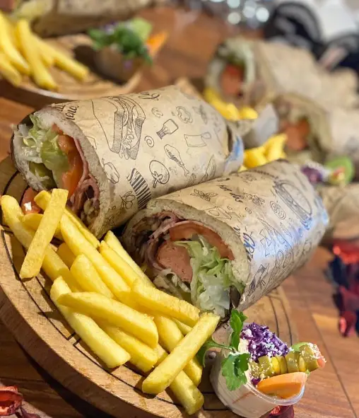 تصویر یک وعده کامل فست فود بلوط: دو ساندویچ لذیذ ساب یا هات داگ با سیب زمینی سرخ کرده طلایی و سالاد تازه. بهترین گزینه فست فود.