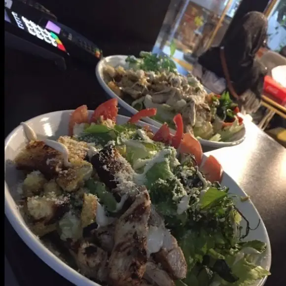 تصویری از دو بشقاب سالاد سزار با مرغ گریل، کاهو، گوجه و پنیر در فست فود بلوط. انتخابی سالم و خوشمزه برای مشتریان.