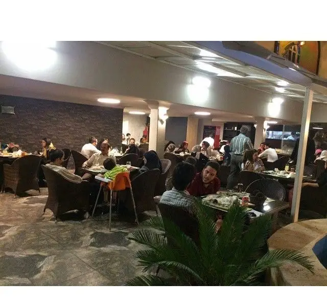 نمایی دلنشین از کافه رستوران کوهسار در شب، مشتریان در حال لذت بردن از غذا و فضای آرامبخش. محیطی خانوادگی و صمیمی.