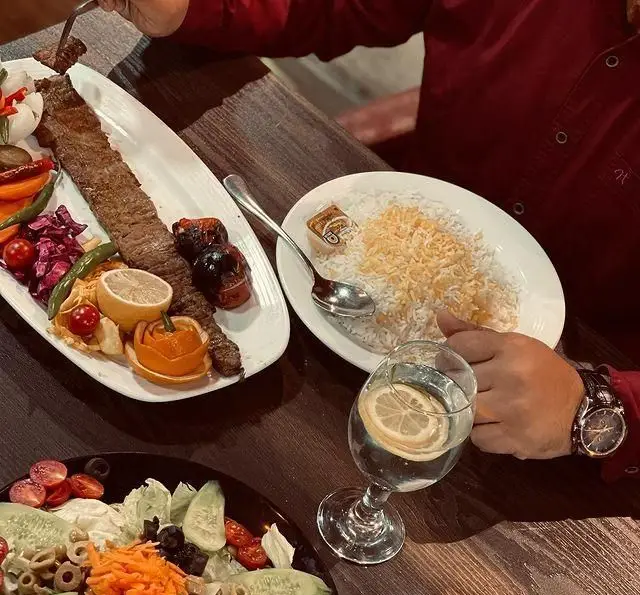 باغ رستوران طبیعت: لذت چشیدن کباب کوبیده و چلو به همراه سالاد تازه، یک غذای سنتی ایرانی در فضایی دلپذیر.