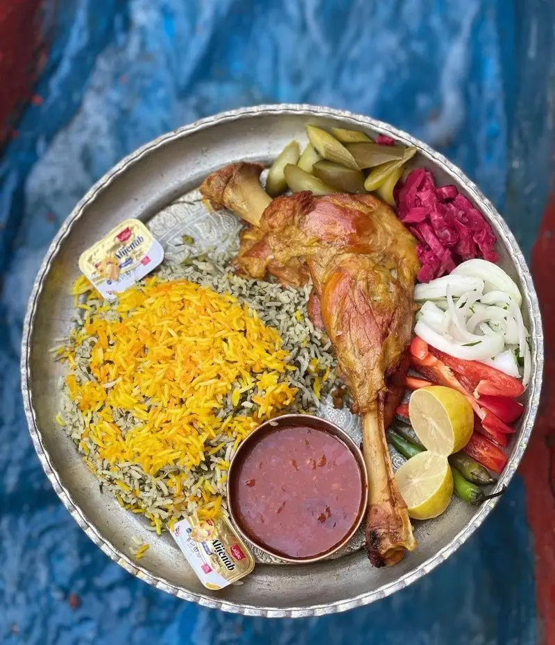 غذای سنتی ایرانی: چلوگوشت بره آبدار و برشته با پلو زعفرانی و باقالی پلو، سس مخصوص و مخلفات در باغ رستوران طبیعت.