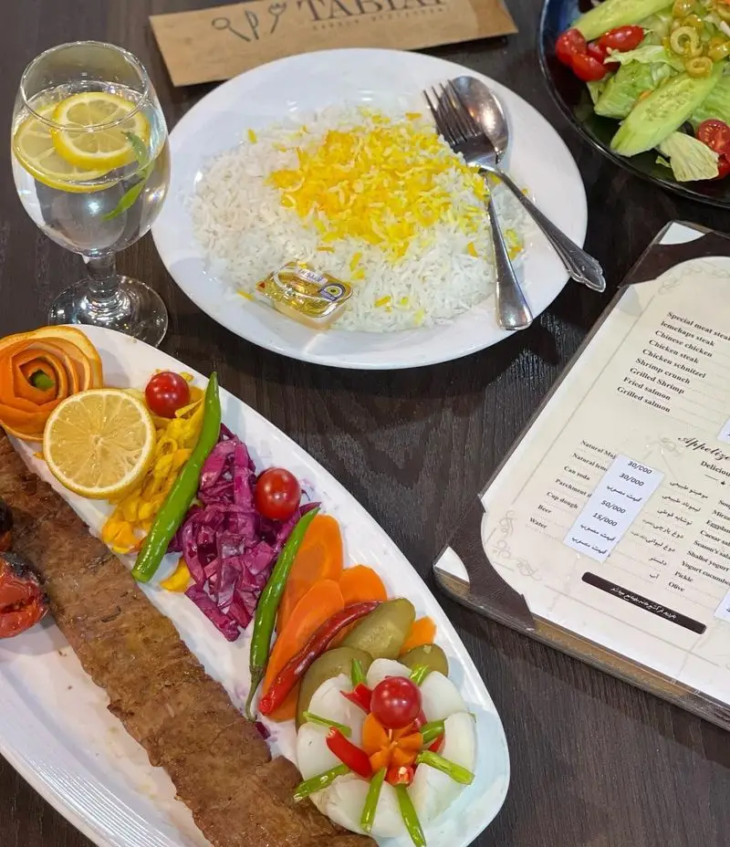 سینی کباب با برنج زعفرانی، سالاد و انواع مخلفات رنگارنگ در باغ رستوران طبیعت؛ لذت طعم اصیل غذای ایرانی.