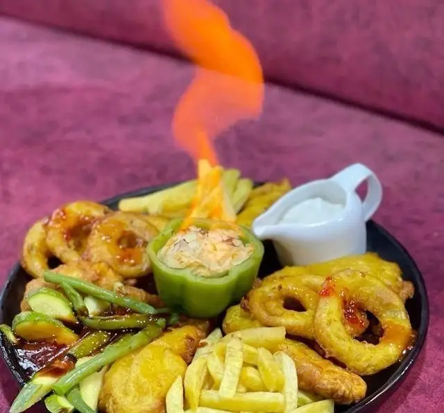 سینی غذای کامل و جذاب باغ رستوران طبیعت شامل پیاز سوخاری، سیب زمینی سرخ شده، سبزیجات گریل و دیپ فلفل شعله‌ور برای تجربه‌ای خاص.