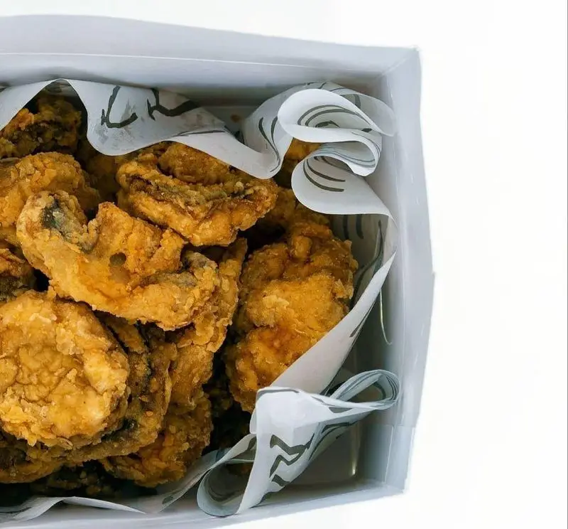 مرغ سوخاری ترد و طلایی کابوکی، در جعبه‌ای شیک و سفید با کاغذ الگودار، آماده برای لذت یک وعده غذایی عالی و فراموش‌نشدنی.