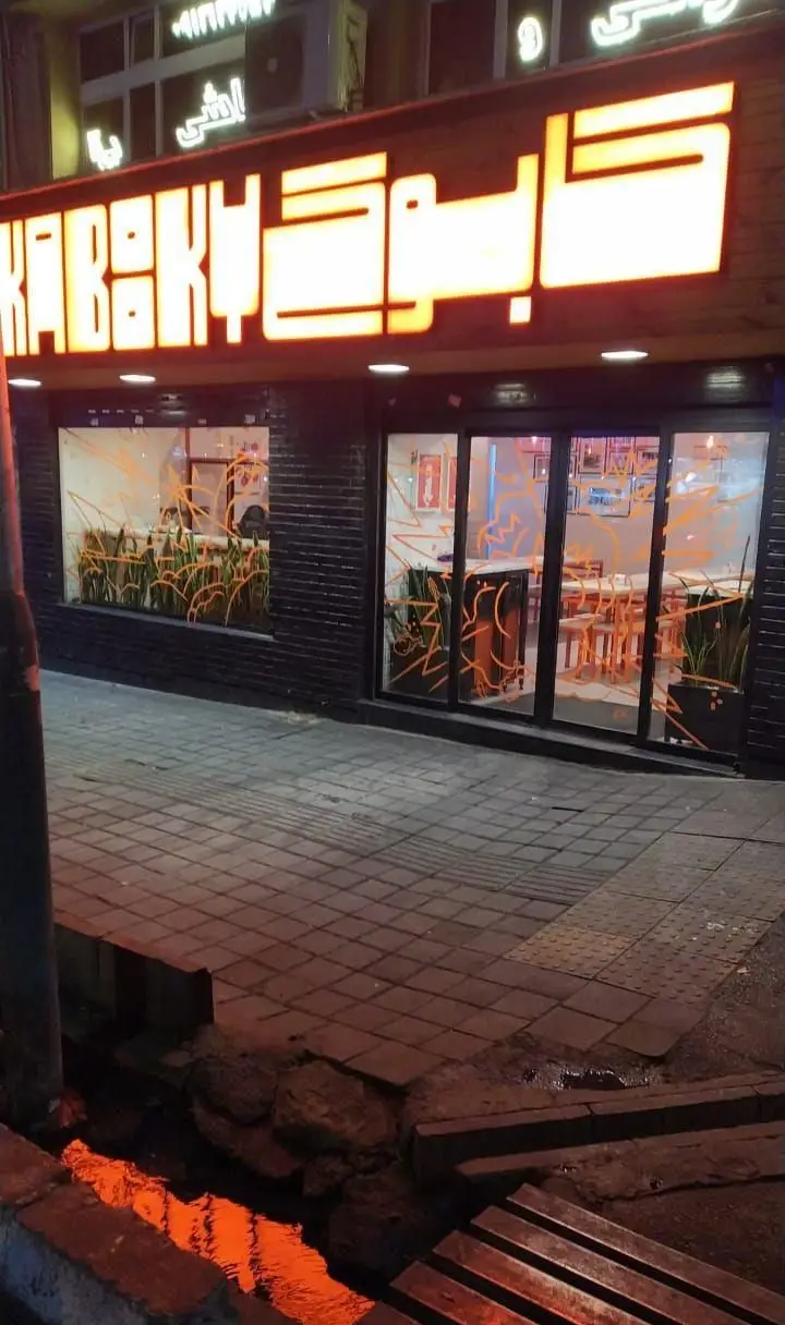 نمای بیرونی رستوران مرغ سوخاری کابوکی در شب با تابلوی نئون نارنجی و دکوراسیون داخلی مدرن، آماده پذیرایی از مشتریان.