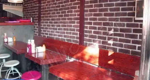 دکوراسیون داخلی دلنشین دکان برگر با دیوار آجری، میز و صندلی‌های چوبی شیک و فضای آرام، مکانی عالی برای صرف غذا.