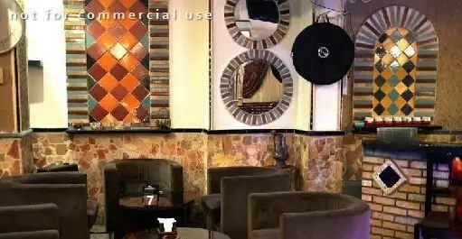 دکوراسیون داخلی سفره خانه مروارید، شامل کاشی‌کاری‌های رنگارنگ، دیوار سنگی، آینه‌های دایره‌ای و میز و صندلی‌های راحتی برای ایجاد فضایی دلپذیر.