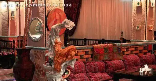 فضای داخلی سفره خانه سنتی مروارید با دکوراسیون اصیل، کوسن‌های قرمز، دیوار آجری، آینه و مجسمه، محیطی دلنشین و آرامش‌بخش.