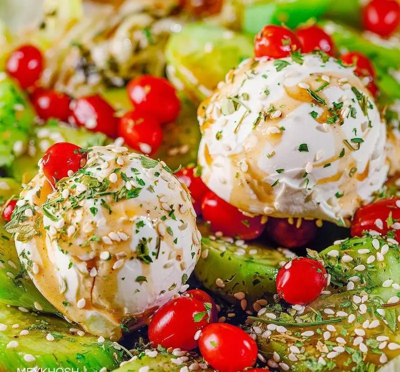 سالاد ویژه و تازه پیتزا میخوش با پنیر بوراتا، گوجه گیلاسی، آووکادو، کنجد و سس بالزامیک. پیش غذایی سالم و لذیذ.