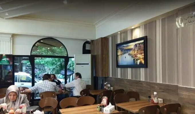 محیط داخلی دنج و دلنشین پیتزا میخوش، با مشتریانی که در حال صرف غذای فست فود و پیتزا در فضایی گرم و دوستانه هستند.