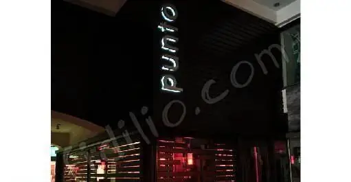 نمای بیرونی شبانه رستوران برگر پونتو با تابلوی نئون درخشان "punto" و ورودی شیک. محیطی جذاب و مدرن برای تجربه بهترین برگرها و فست فود.
