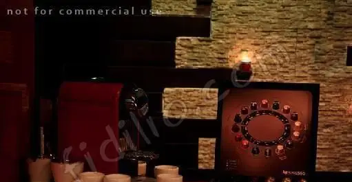 ایستگاه قهوه نسپرسو لوکس در برگر پونتو، شامل دستگاه قرمز، دیسپلی کپسولها و فنجانها در فضایی با دیوار سنگی و نور گرم.