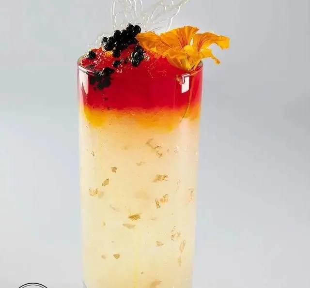 نوشیدنی یا دسر لایه‌لایه و خاص کافه رستوران مگریز، با ترکیبی از رنگ‌های شاد و تزئینات لوکس مانند گل خوراکی و پولک طلا.