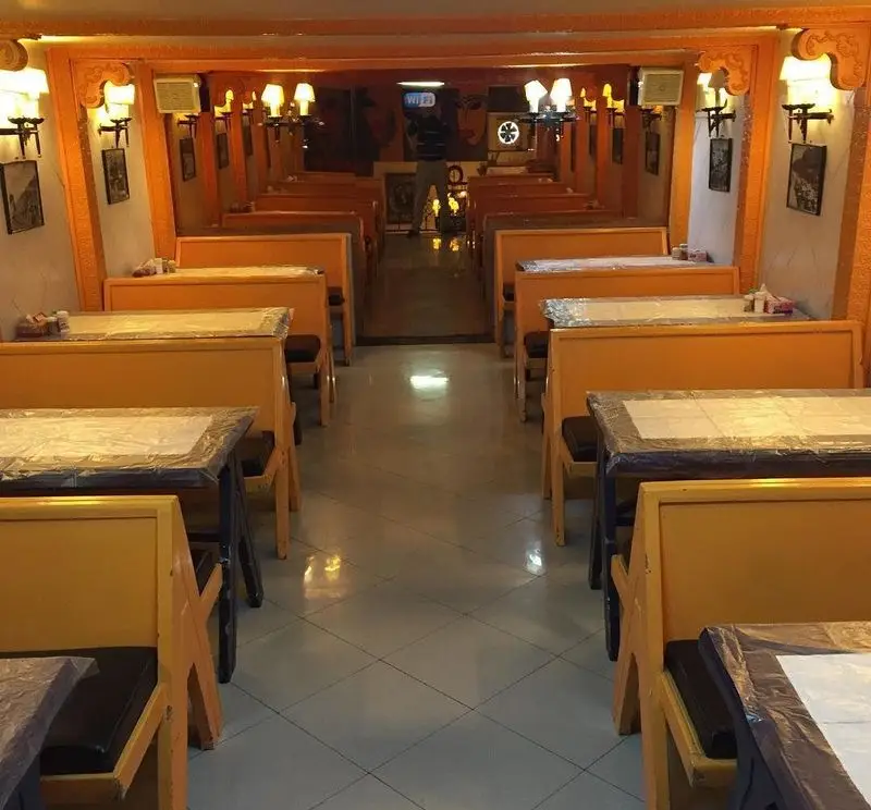 فضای داخلی دنج و تمیز رستوران پیتزا پارس، با میز و صندلی‌های چوبی نارنجی و دکوراسیون گرم و سنتی، آماده خدمات‌رسانی.