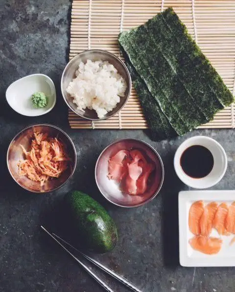 مواد اولیه سوشی رستوران واسابی: برنج، نوری، سالمون، آووکادو، واسابی، گاری و سس سویا آماده برای تهیه غذای ژاپنی.