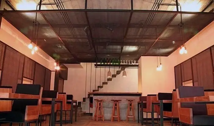 فضای داخلی دنج و مدرن رستوران واسابی با دکوراسیون صنعتی، میز و صندلی چوبی شیک، بار و نورپردازی گرم، محیطی عالی برای مشتریان.