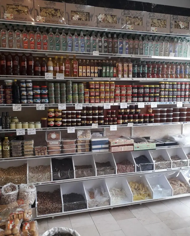 تصویری از فروشگاه لبنیات سنتی ناصری لیقوانی با قفسه‌های متنوع عرقیجات، شربت، عسل، مربا، آجیل، خشکبار و ادویه‌جات سنتی.