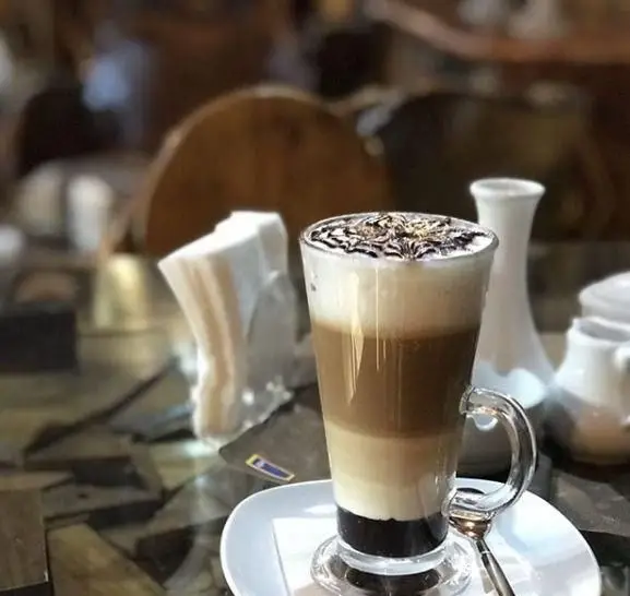 تصویری از یک فنجان قهوه لایه ای زیبا با تزئین شکلاتی در سفره خانه سنتی چهل ستون، بهترین نوشیدنی گرم برای لحظات آرامش‌بخش.