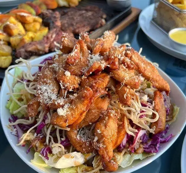 لذت طعم بی‌نظیر سالاد مرغ سوخاری ترد با پنیر پارمزان و نودل‌های کریستالی در کافه رستوران دریا باز، انتخابی عالی برای نهار یا شام.