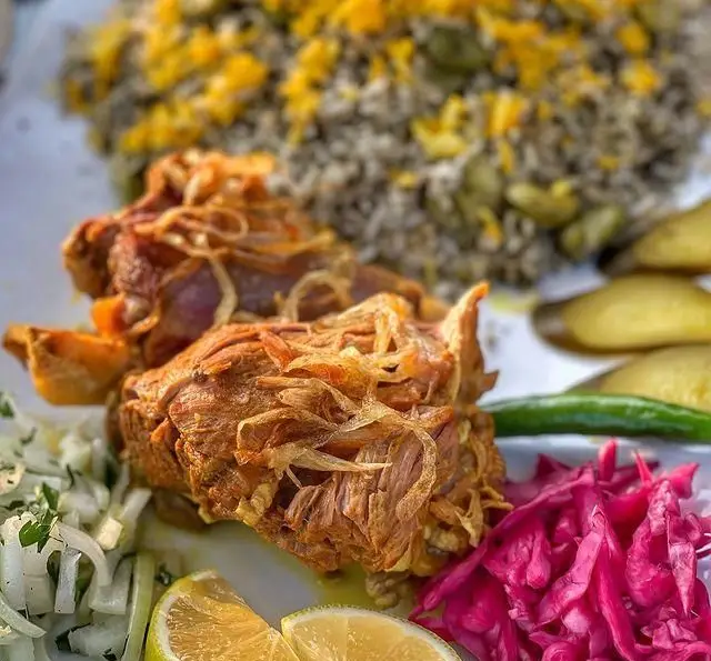 بشقاب غذای سنتی ایرانی شامل باقالی پلو با گوشت بره یا گوساله، پیاز داغ، لیمو و سبزیجات تازه در کافه رستوران دریا باز.