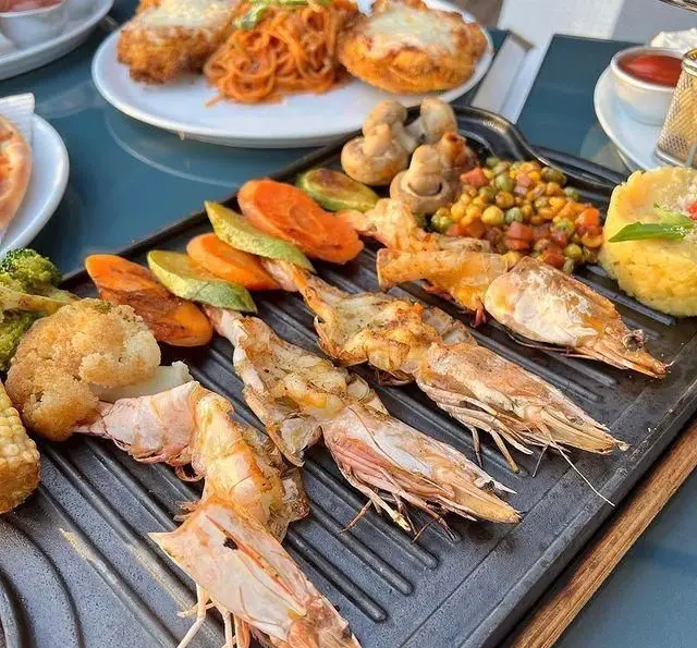 سینی متنوع غذای دریایی شامل میگو کبابی، سبزیجات و پاستا. لذت طعم‌های تازه را در کافه رستوران دریا باز تجربه کنید.