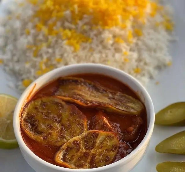 تصویری جذاب از خورش بادمجان اصیل و خوش طعم کافه رستوران دریا باز همراه با پلو زعفرانی و مخلفات تازه برای تجربه‌ای لذت‌بخش.