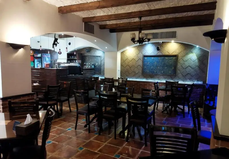 فضای داخلی زیبا و دنج رستوران سنتی عمارت با میز و صندلی‌های چوبی، سقف و دیوارهای سنتی و دکوراسیون دلنشین کافه