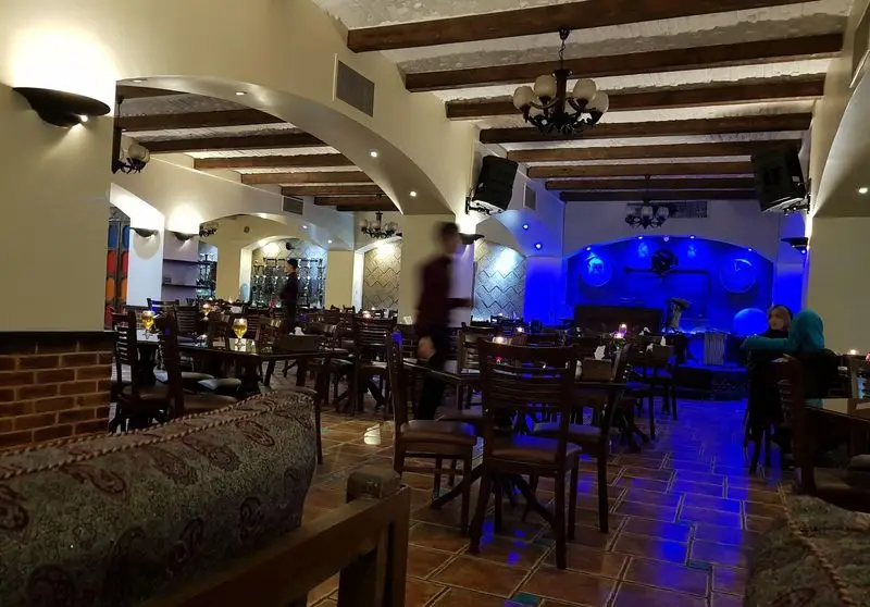 فضای داخلی دلنشین و دکوراسیون سنتی رستوران عمارت با نورپردازی آبی، محیطی ایده‌آل برای صرف غذا و موسیقی زنده فراهم کرده است.