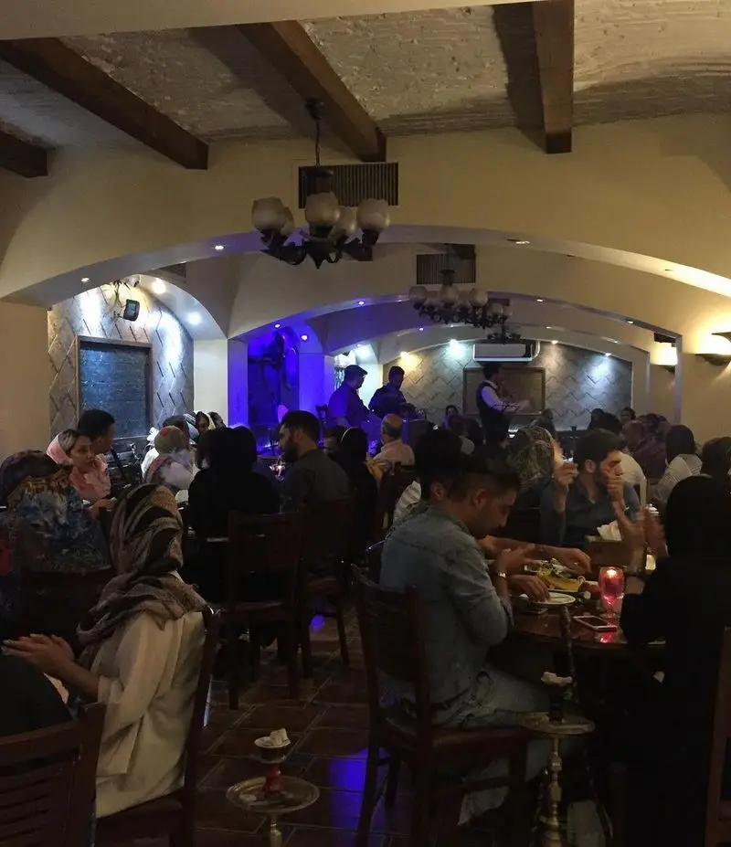 فضای دلنشین و شلوغ رستوران سنتی عمارت با مشتریان در حال صرف غذا، قلیان و لذت بردن از موسیقی زنده و دورهمی شبانه.