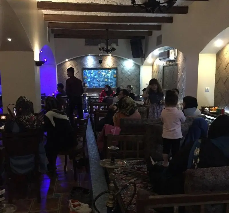 فضای شلوغ رستوران سنتی عمارت با مشتریان متعدد و دکوراسیون سنتی، مکانی ایده‌آل برای دورهمی خانوادگی.