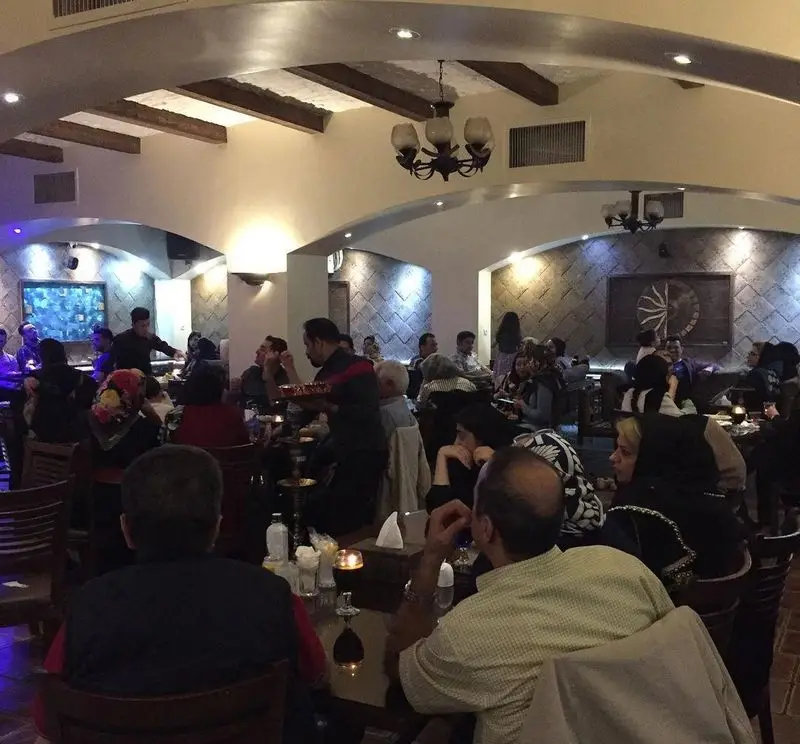 فضای داخلی رستوران سنتی عمارت با مشتریان متعدد، دکوراسیون سنتی زیبا، نورپردازی گرم و محیطی دلنشین و آرامش‌بخش برای صرف غذا.