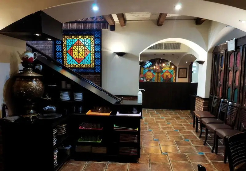 فضای داخلی چشم‌نواز رستوران سنتی عمارت با پنجره‌های ارسی (شیشه‌رنگی) زیبا، سماور سنتی و معماری اصیل ایرانی.