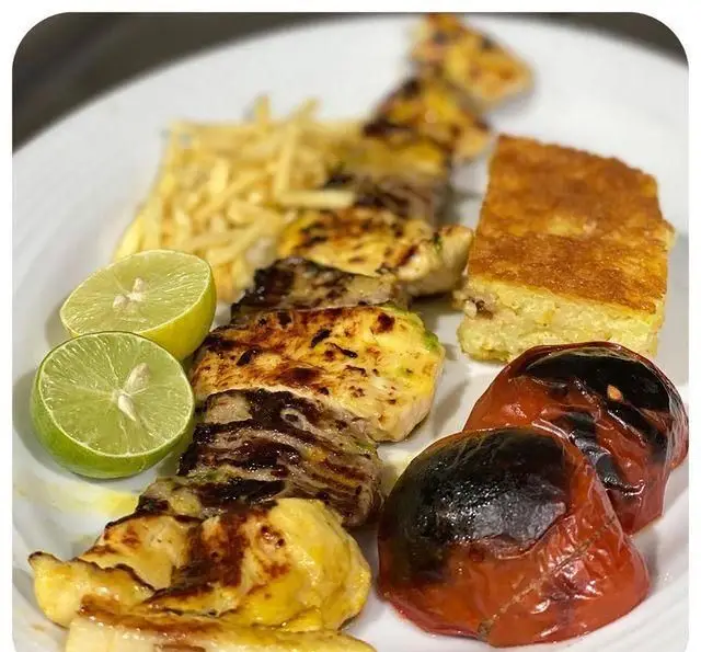 جوجه کباب ممتاز رستوران سید در شهرری با ته چین زعفرانی، گوجه کبابی، لیمو تازه و سیب زمینی ترد. تجربه غذای ایرانی اصیل.