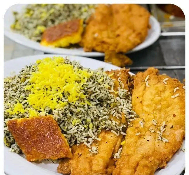 یک بشقاب کامل سبزی پلو با ماهی سرخ شده ترد و ته دیگ زعفرانی طلایی از رستوران سید شهرری. بهترین غذای ایرانی.
