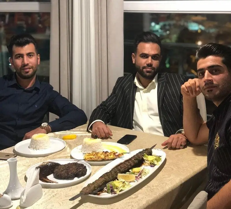 لحظات دلنشین سه مرد در رستوران پرشین گلف، هنگام صرف شام با کباب کوبیده و جوجه به همراه برنج و سالاد، تجربه‌ای لذت‌بخش از غذای اصیل ایرانی.