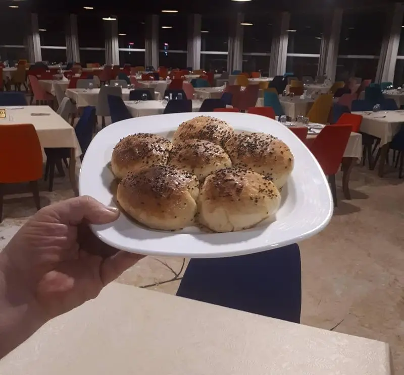 تصویری از نان‌های خانگی و خوش‌عطر با کنجد، آماده سرو در رستوران پرشین گلف. محیطی دنج و شیک برای تجربه غذایی دلپذیر.