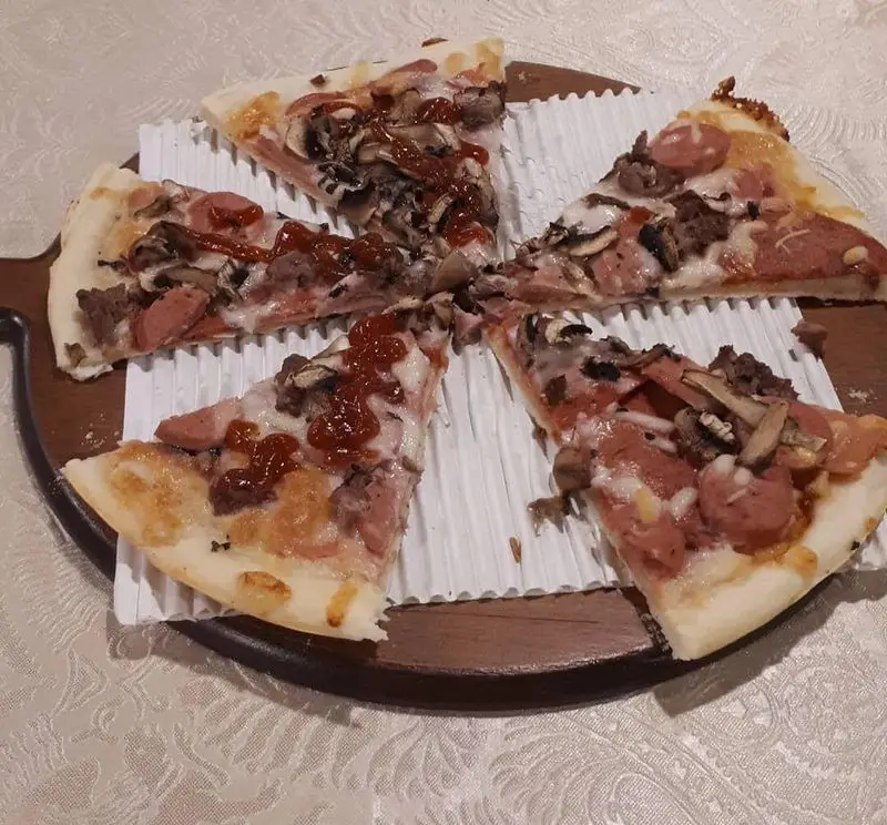 پیتزا با سوسیس، قارچ و گوشت چرخکرده، سرو شده در رستوران پرشین گلف؛ طعمی بی‌نظیر برای هر سلیقه‌ای.