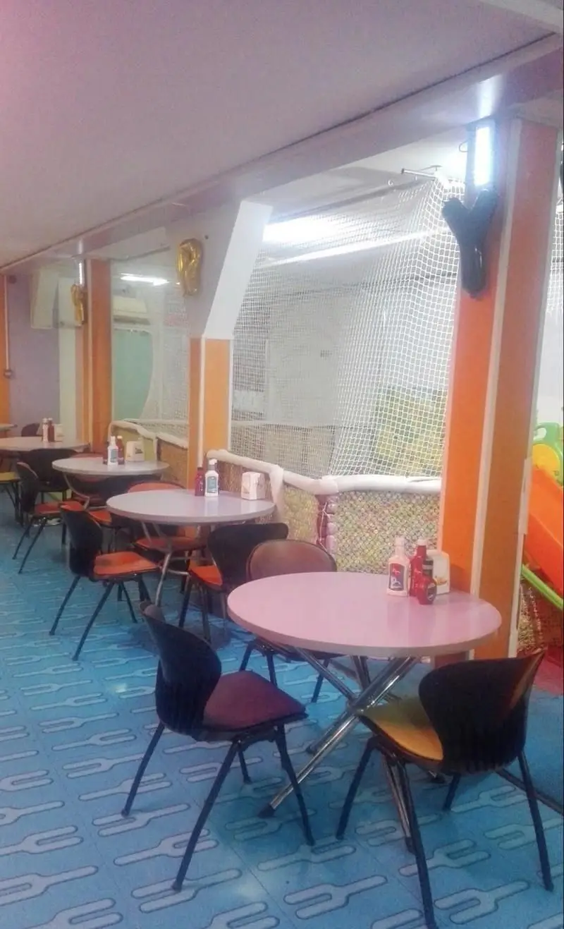 فضای داخلی و دنج فست فود مادر با میز و صندلی‌های راحت، مشرف به فضای بازی کودکان. انتخابی عالی برای خانواده‌ها.