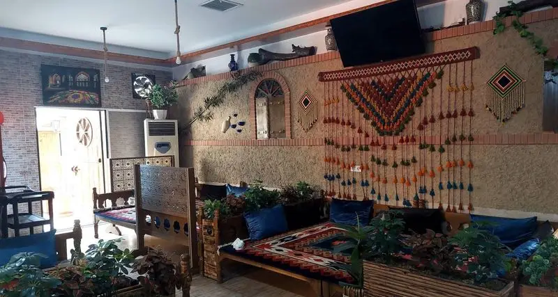 فضای داخلی کافه و رستوران سنتی سپه با دکوراسیون دلنشین ایرانی، تخت‌های چوبی، فرش، گلدان و آویزهای رنگی سنتی.