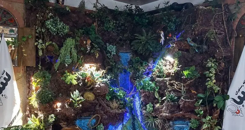 دکوراسیون داخلی کافه رستوران سنتی سپه با آبنمای آبی، فضای سبز مصنوعی و تزیینات سنگی، محیطی دلنشین و آرامش‌بخش.