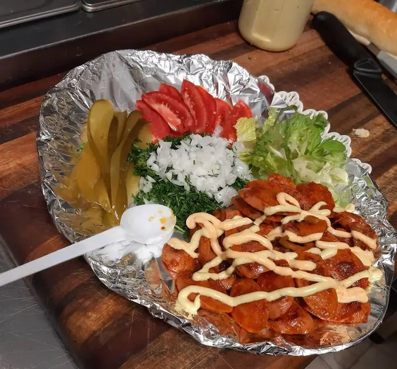 ساندویچ شاپ مزه فرنگ: سوسیس داغ گریل‌شده با سس مخصوص، مخلفات تازه گوجه، پیاز، خیارشور، کاهو و سبزیجات. غذای آماده خوشمزه