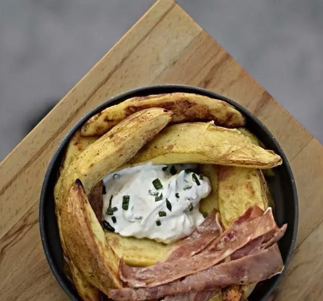 سیب‌زمینی وجز با سس مخصوص و بیکن ترد در کافه رستوران پلاک ٥. غذایی خوشمزه و باکیفیت برای تجربه‌ای دلنشین.