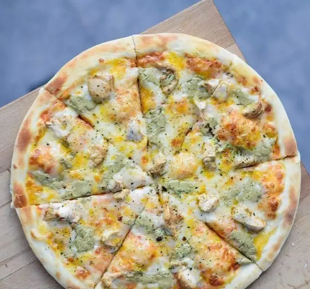 پیتزا مرغ و پستو خوشمزه از كافه رستوران پلاك ٥، با پنیر فراوان و تکه‌های مرغ مکعبی و سس پستو معطر، آماده سرو.