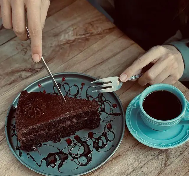 برش کیک شکلاتی لذیذ در کافه رستوران پلاک ٥، همراه با قهوه‌ای دلپذیر در فضایی آرام و دلنشین.